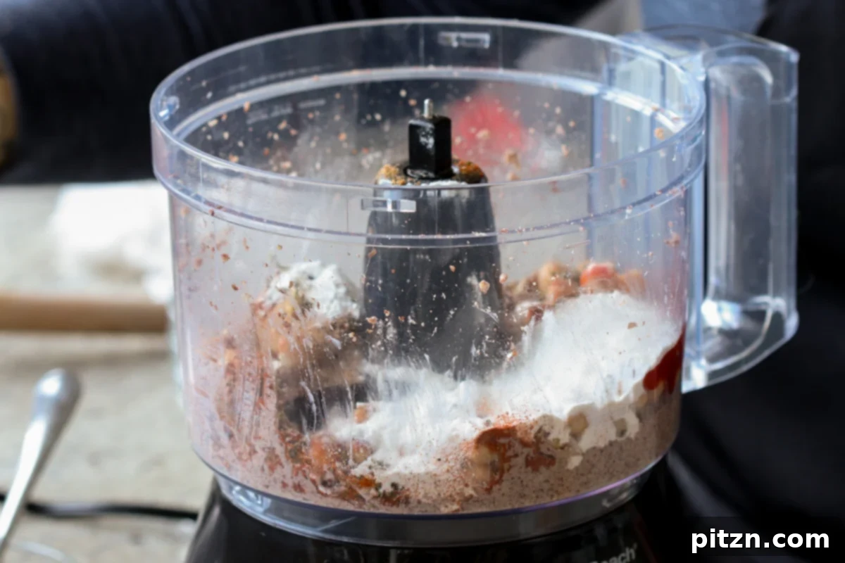Spices and flour being added to the chickpea and pecan mixture in the food processor, ready for the next blending stage.