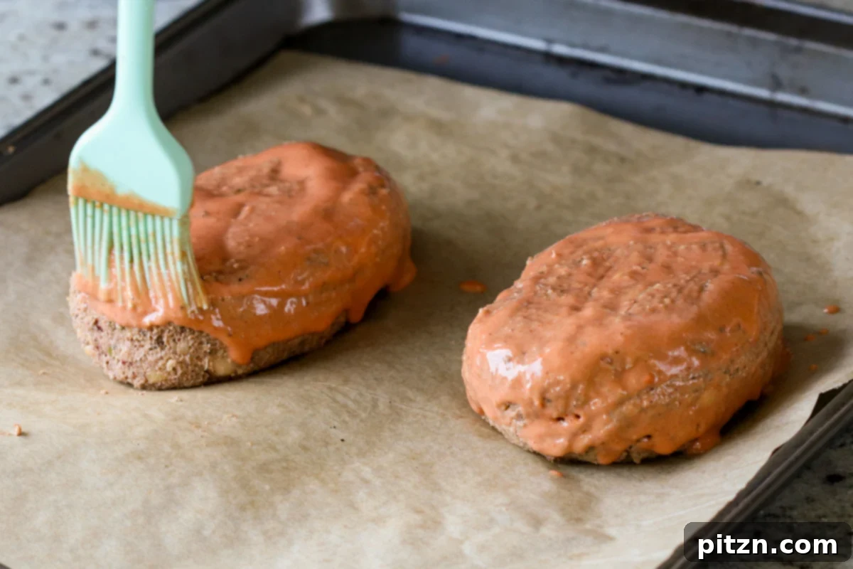 A brush applying a luscious layer of Indian butter sauce onto the raw chickpea loaves, preparing them for baking and glazing.