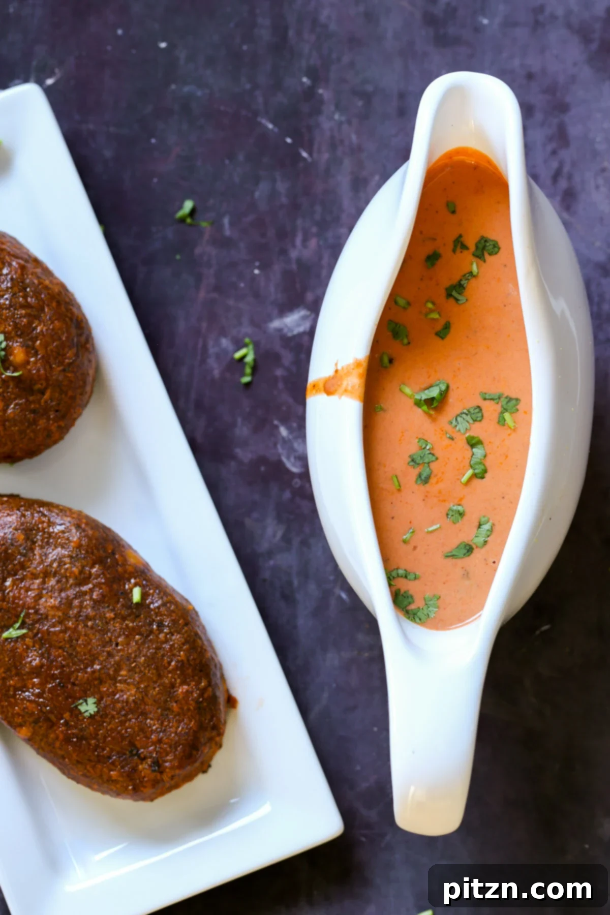 A elegant gravy boat filled with luscious Indian butter chicken sauce, positioned next to the perfectly baked spiced chickpea loaves, ready to be served.