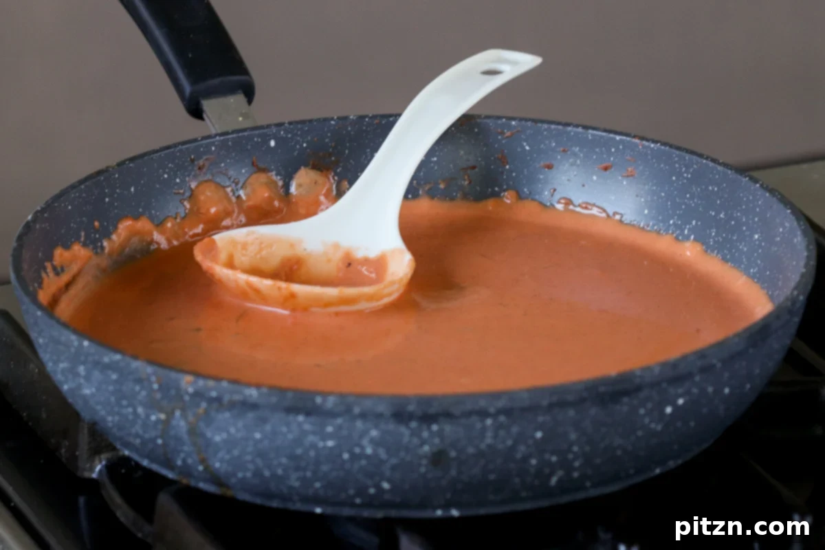 A close-up of the vegan butter chicken sauce simmering beautifully in a pan on the stovetop, showcasing its rich, creamy texture.