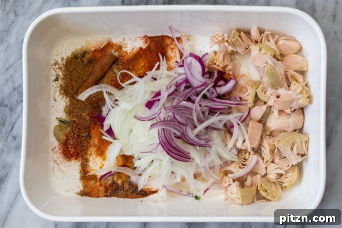 Thinly sliced red onions added to the baking dish with the seasoned jackfruit and spices.