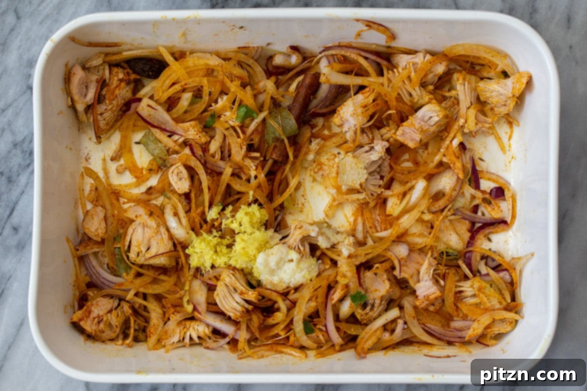 The jackfruit, onions, and spices after being mixed thoroughly in the baking pan.