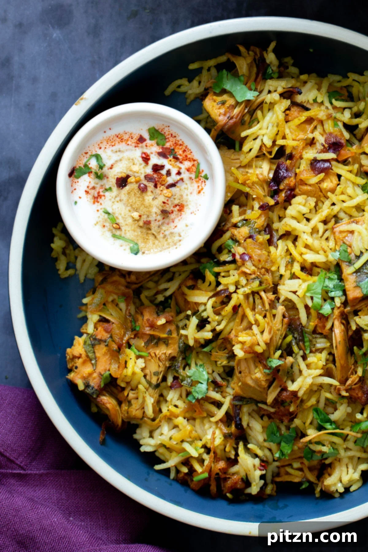 A serving of baked jackfruit biryani with a side of cooling raita, ready to be enjoyed.