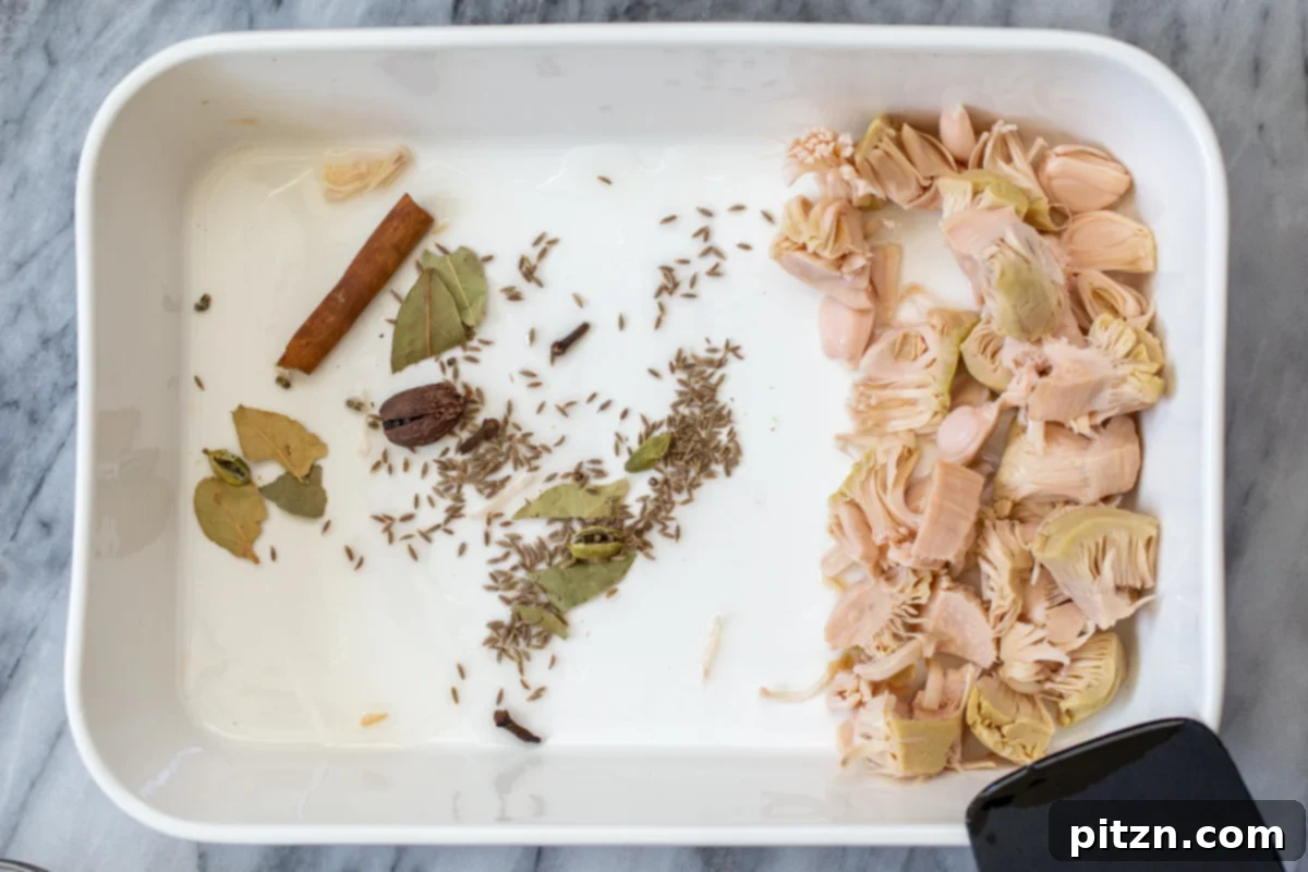 Prepared jackfruit and whole spices arranged in a baking pan before the first bake.
