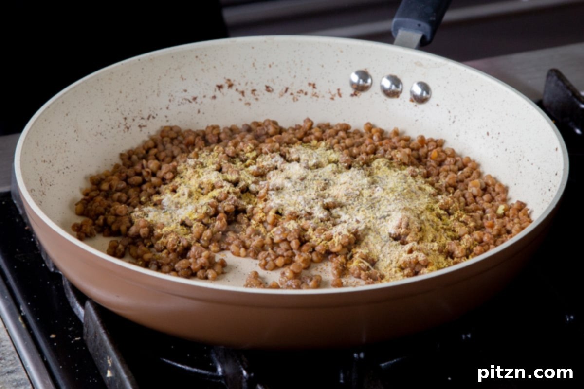 Popped Lentils and Whipped Potatoes 13 Adding a generous amount of spices to the freshly popped lentils in the pan, ensuring even coating.