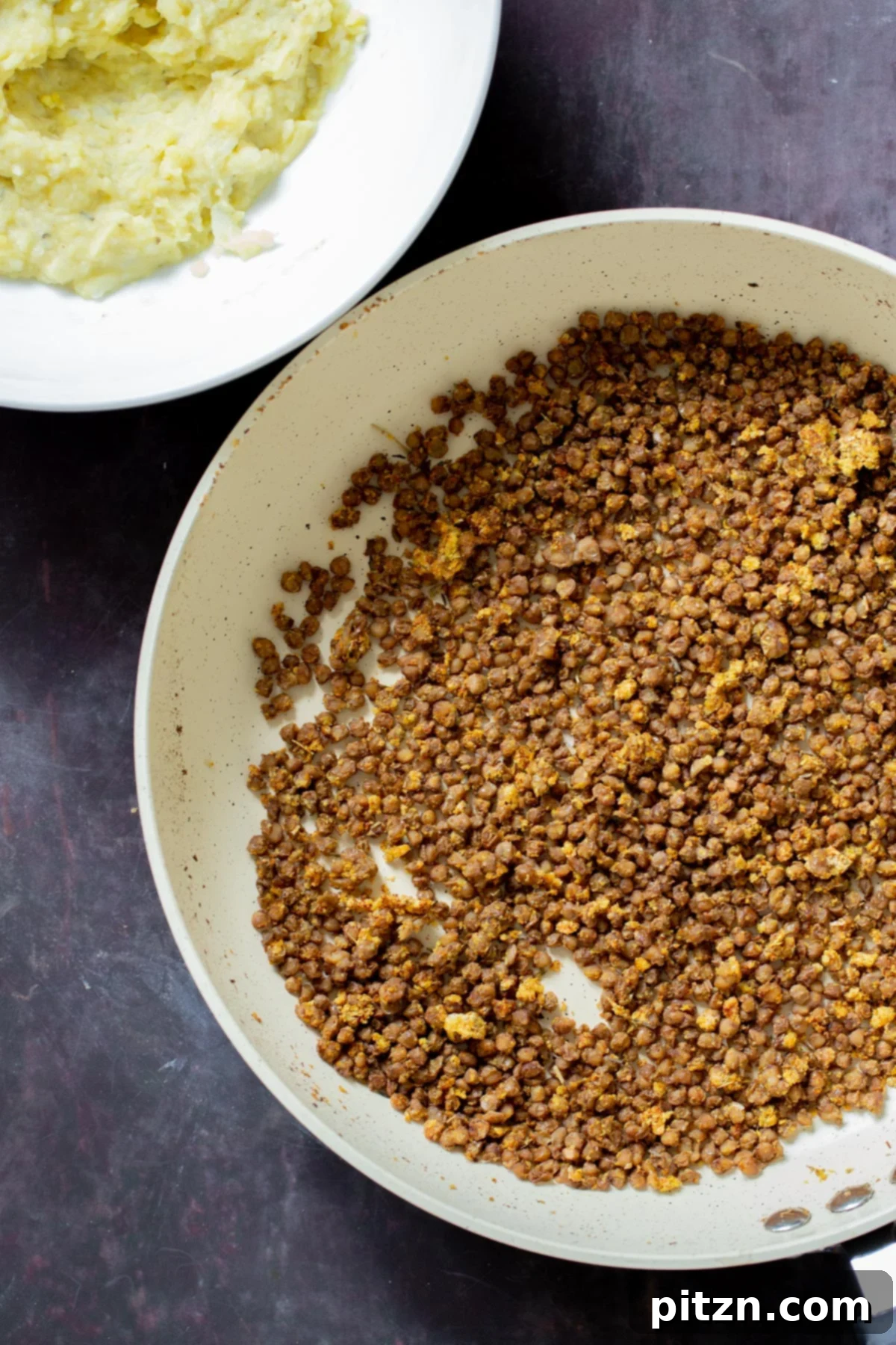 Popped Lentils and Whipped Potatoes 4 Close-up shot of crispy, spiced lentils sizzling in a frying pan, illustrating the 'popping' process.