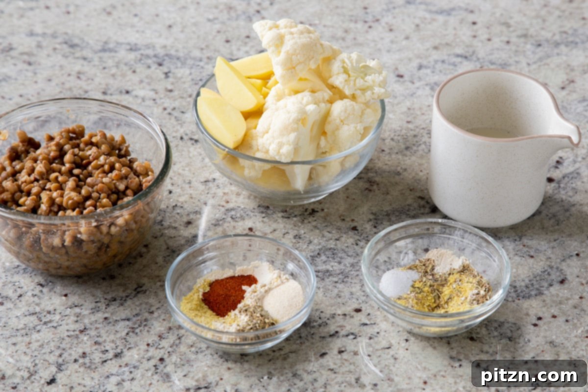 Popped Lentils and Whipped Potatoes 5 An array of fresh ingredients for Popped Lentil Mashed Potatoes, including cauliflower, potatoes, and spices, laid out on a kitchen counter.
