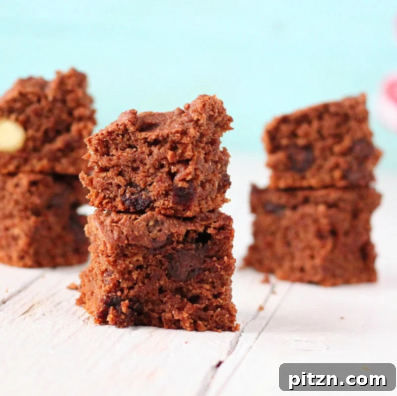 Fudgy Vegan Chocolate Brownies made with dates and coconut oil, stacked on a plate, garnished with fresh berries