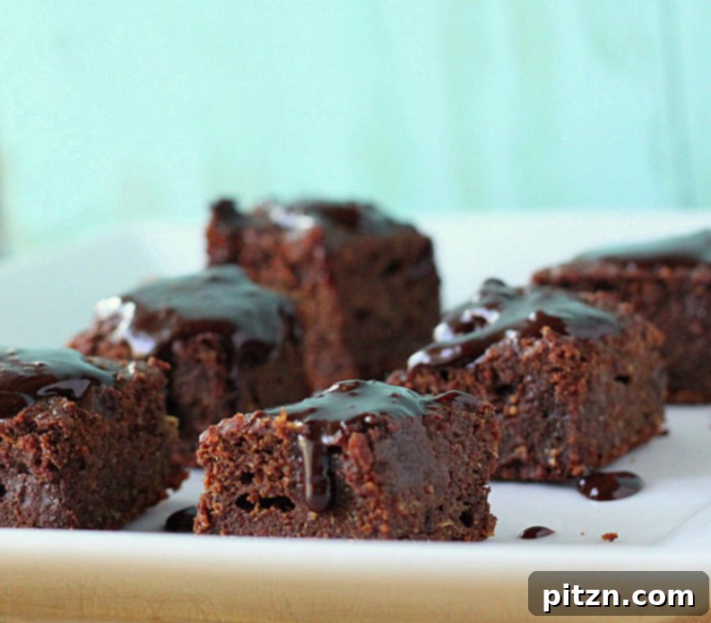 Darker vegan brownies, cut into squares, illustrating the dense and fudgy texture achieved with pureed dates
