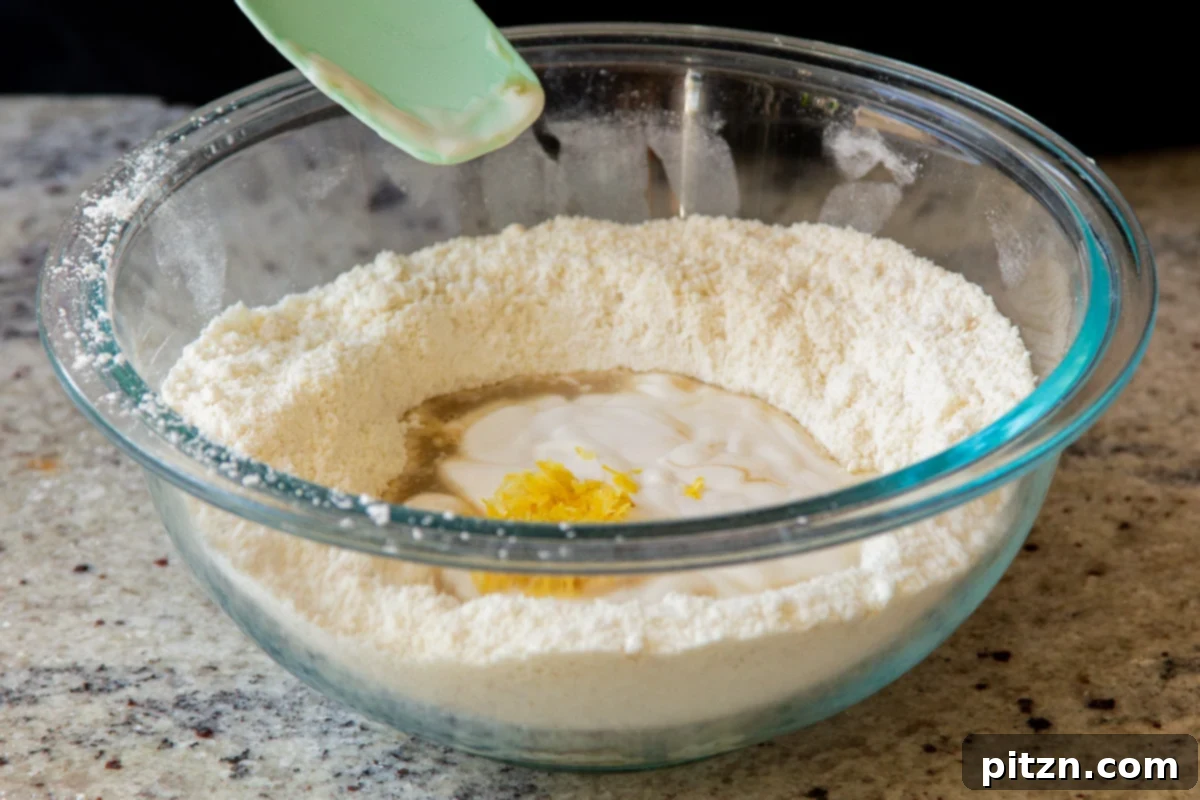 A close-up shot of lemon zest and freshly squeezed lemon juice being added to a bowl of dry pancake ingredients, enriching the mixture with bright, citrusy notes