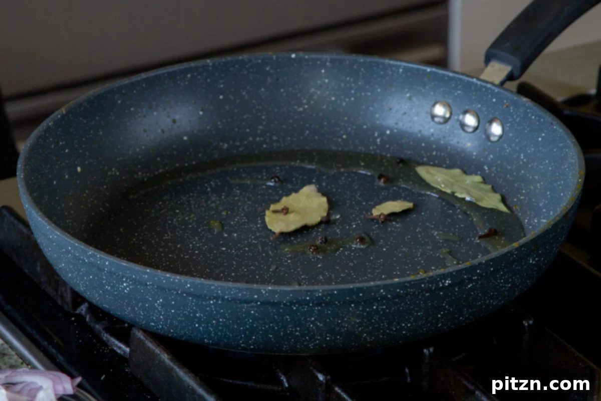 South Indian Black Pepper Tofu Fry 13 Whole spices (bay leaves, cloves, crushed peppercorns) sizzling in oil in a pan