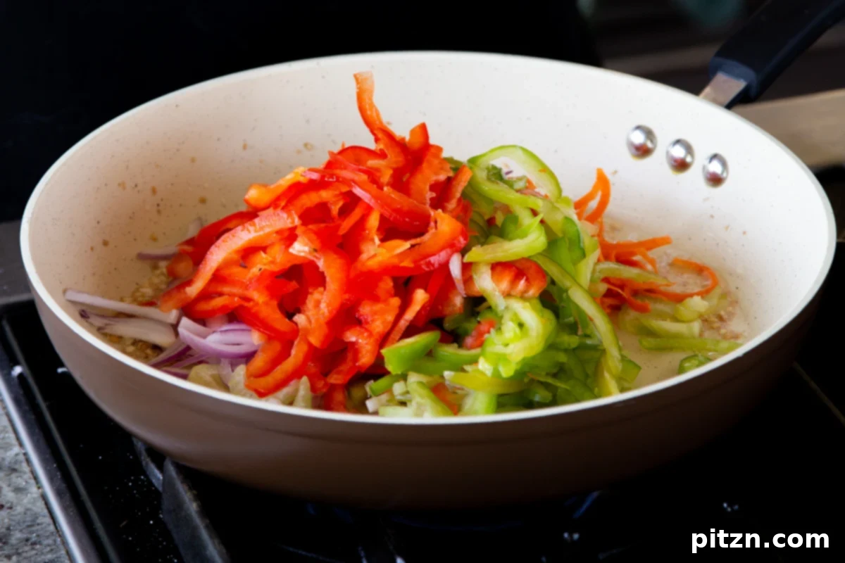 One Pan 30 Minute Schezwan Tofu 10 Chopped bell peppers being added to a pan with other vegetables for stir-frying.