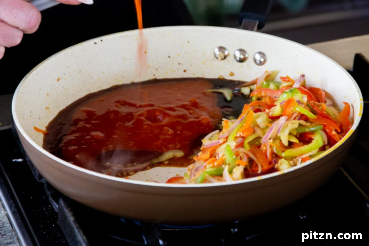 One Pan 30 Minute Schezwan Tofu 11 Various sauces being poured into the pan of sautéed vegetables.