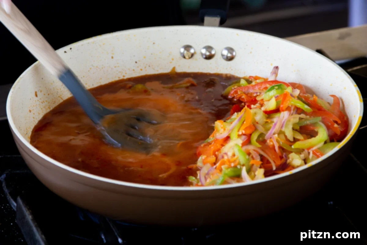 One Pan 30 Minute Schezwan Tofu 12 The Szechuan sauce being stirred in the pan, showing a thickening consistency.