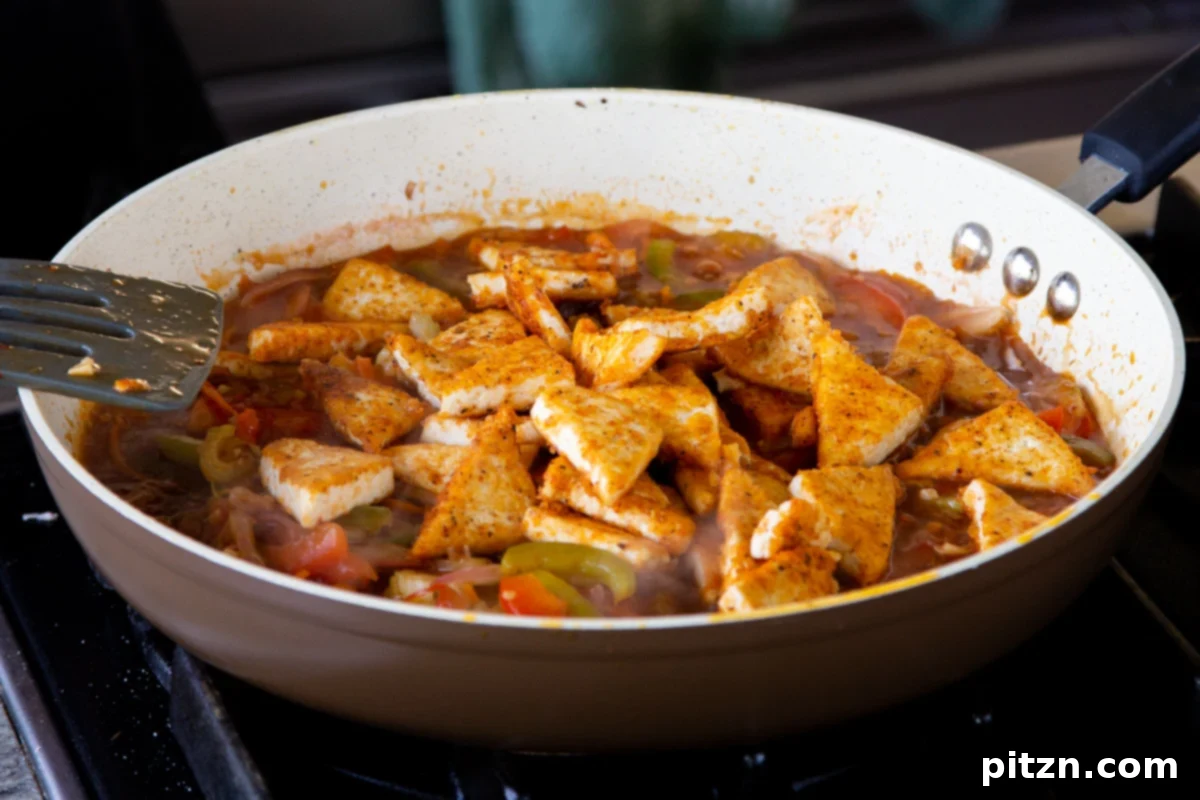 One Pan 30 Minute Schezwan Tofu 14 Crispy tofu being added back into the pan with Szechuan sauce and vegetables.