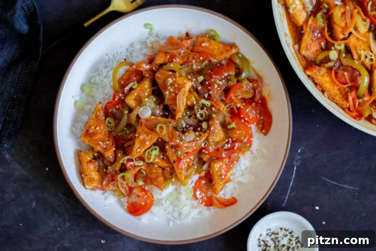 One Pan 30 Minute Schezwan Tofu 16 Szechuan tofu served on a plate with rice, garnished and ready to eat.