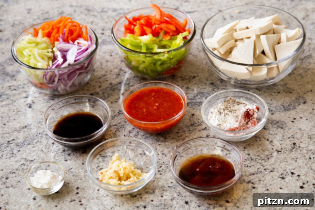 One Pan 30 Minute Schezwan Tofu 6 Bowls of tofu, Szechuan sauce, and various stir-fry ingredients neatly arranged on a kitchen counter, ready for cooking.