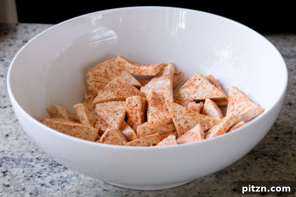 One Pan 30 Minute Schezwan Tofu 7 Seasoned tofu cubes in a white bowl, coated evenly with spices and cornstarch.