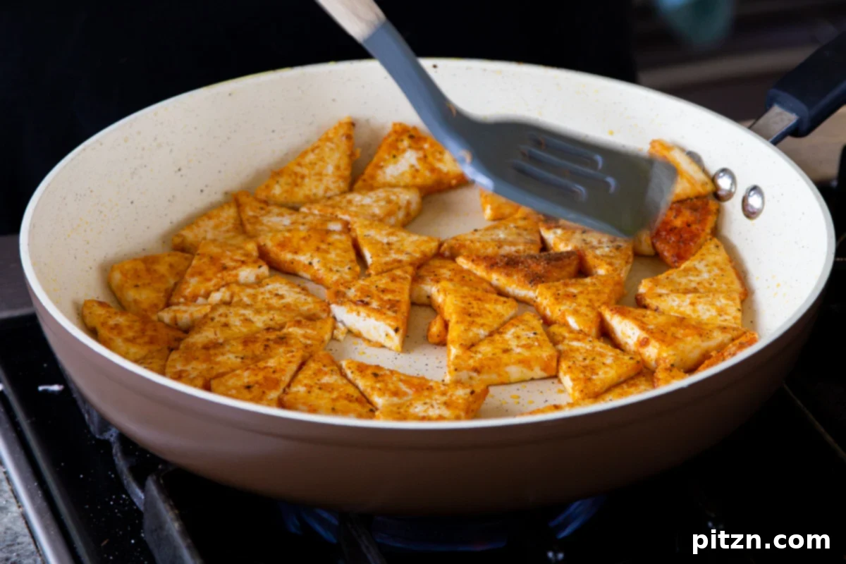One Pan 30 Minute Schezwan Tofu 8 Tofu pieces actively crisping up in a hot pan, turning golden brown.