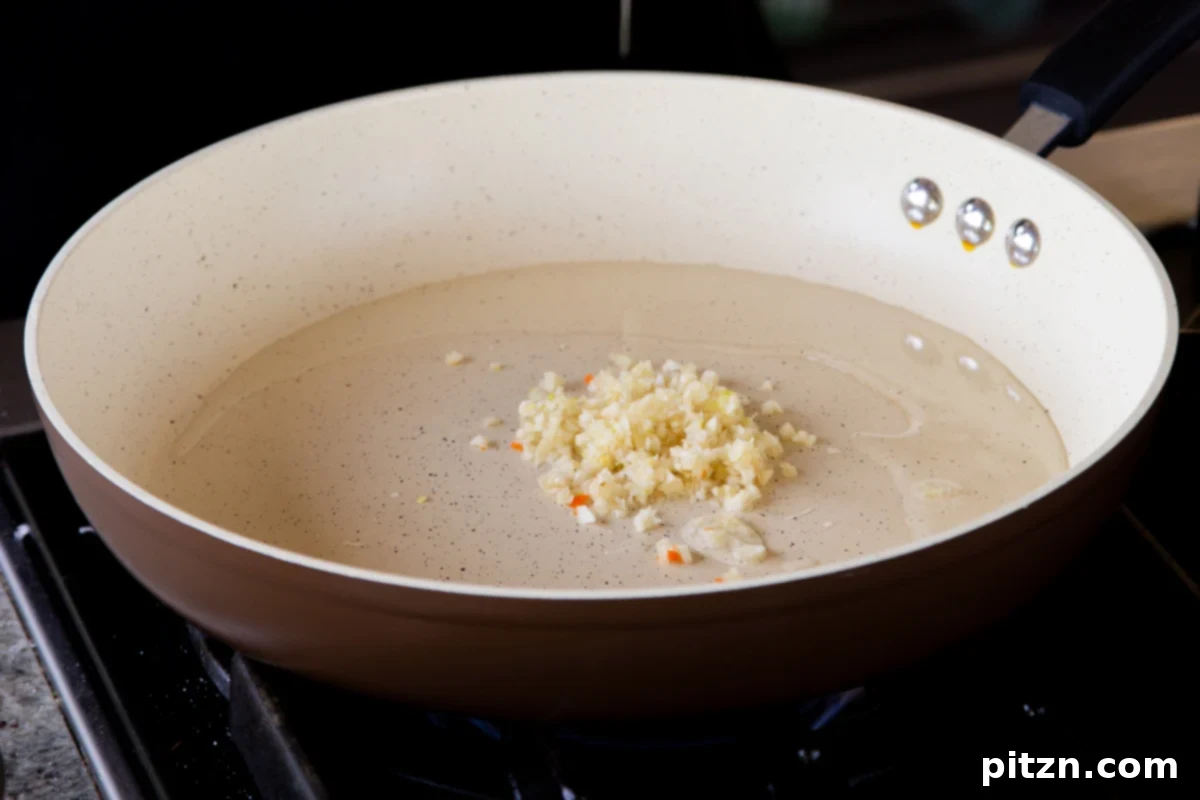 One Pan 30 Minute Schezwan Tofu 9 Minced garlic being added to hot oil in a pan, beginning to sauté.