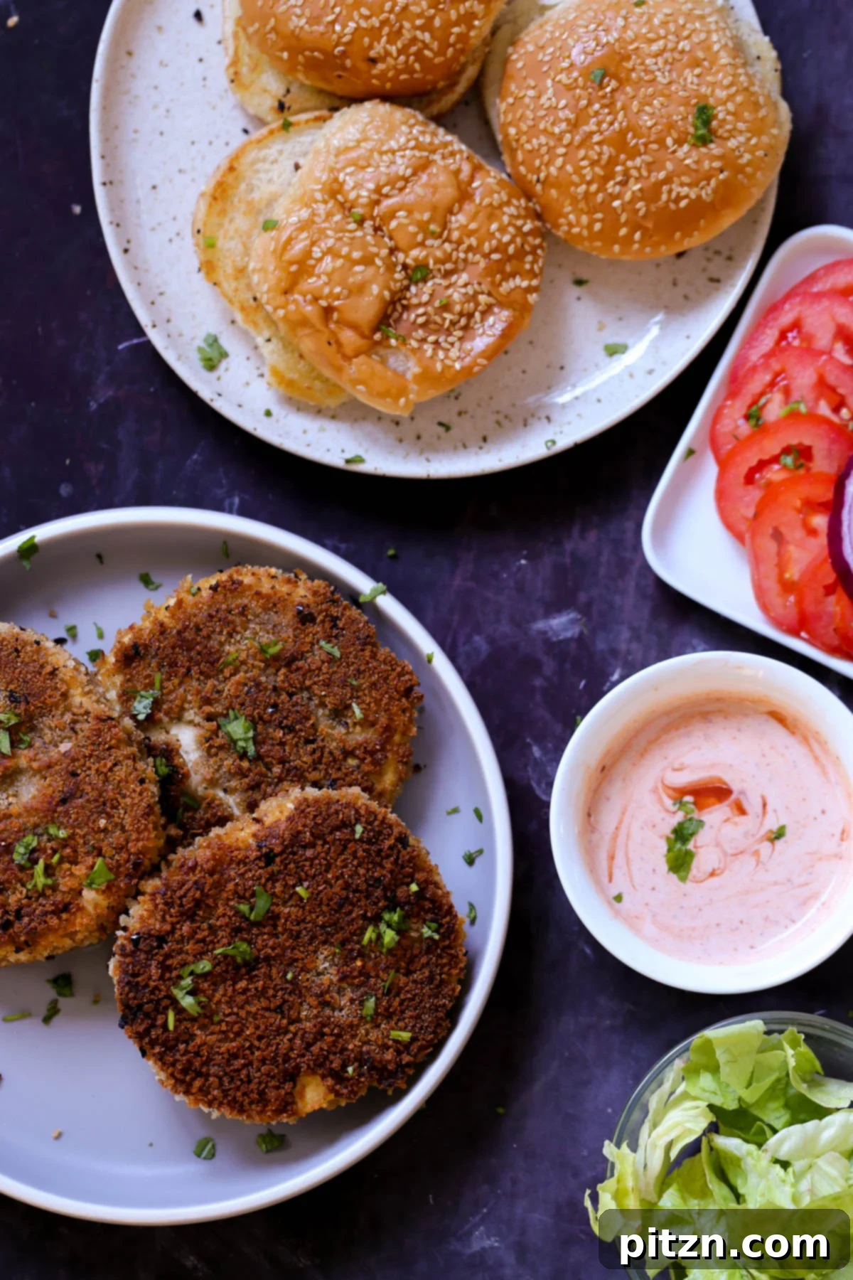 The Inclusive Crispy Vegan Chicken Sandwich 4 crispy vegan chicken patties on a plate with buns and toppings around them