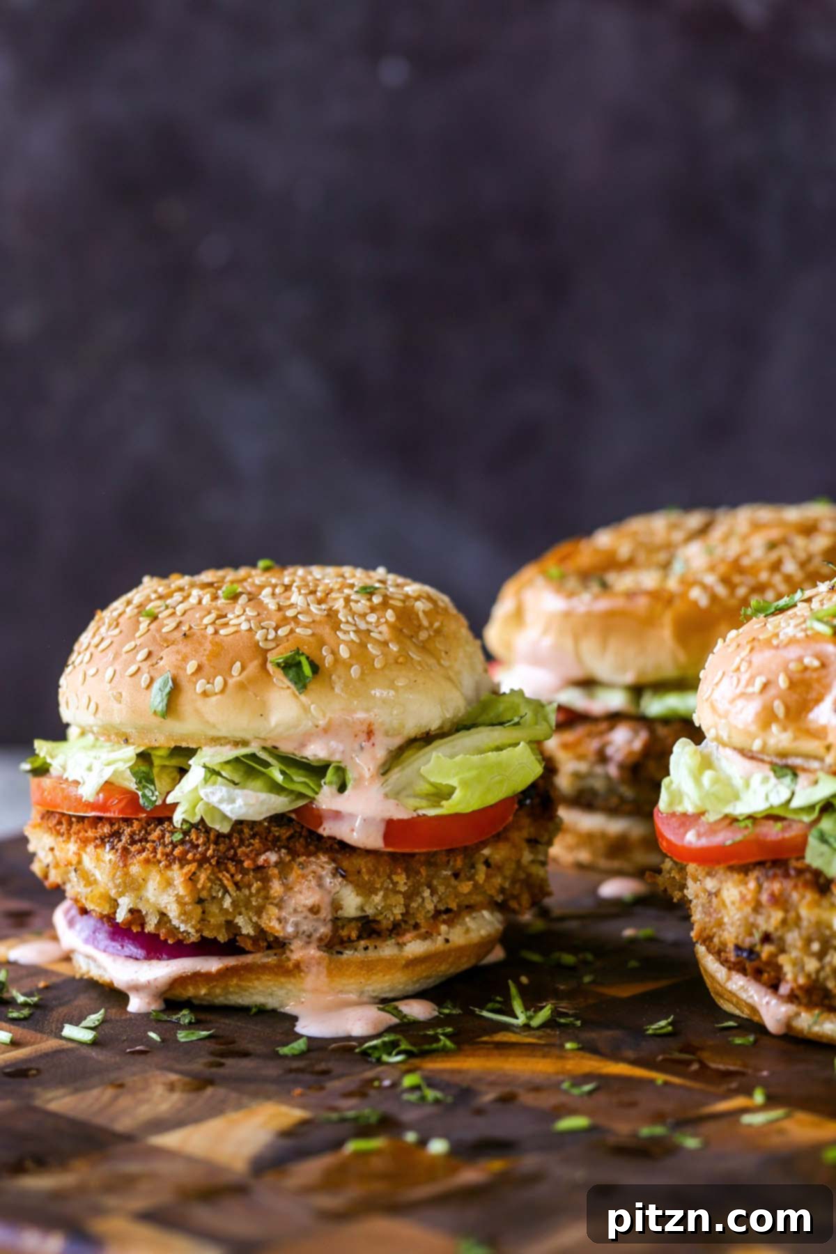 The Inclusive Crispy Vegan Chicken Sandwich 5 crispy vegan chicken sandwiches on a wooden cutting board