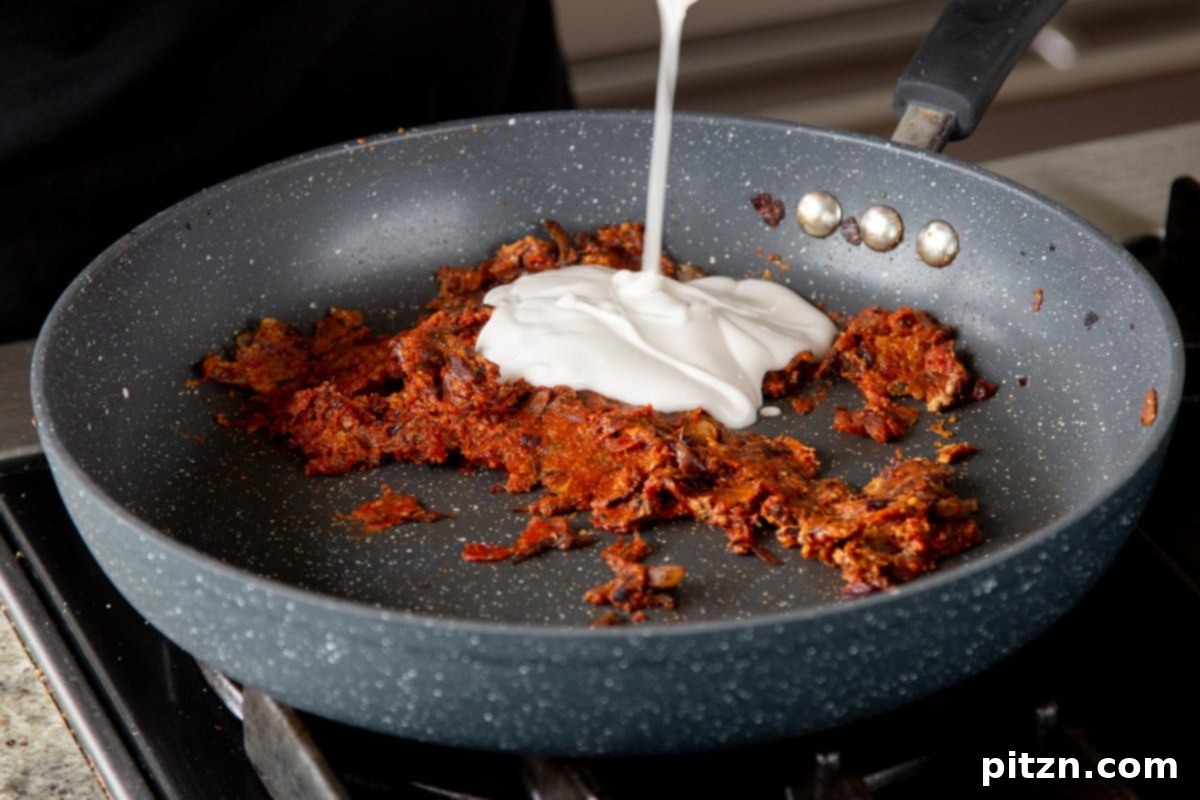 One Pot White Bean Do Pyaza Curry 13 Unsweetened non-dairy yogurt being stirred into the richly spiced onion and tomato paste mixture, adding creaminess.