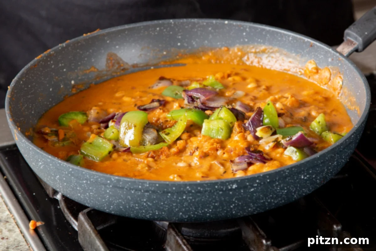 One Pot White Bean Do Pyaza Curry 16 Adding the final touch: the seared onion and bell pepper garnish being stirred into the finished Beans Do Pyaza curry.