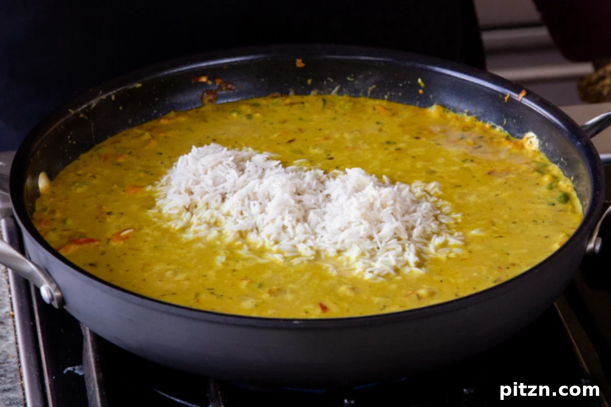 Simple One Pot Jamaican Curry Rice Gluten Free Nut Free 16 Carefully adding washed white rice into the simmering Jamaican curry sauce, ensuring even distribution.