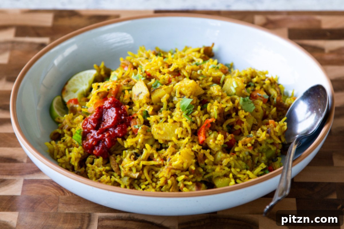 Simple One Pot Jamaican Curry Rice Gluten Free Nut Free 20 A hearty bowl of Vegan Jamaican Curry Rice, garnished with fresh herbs and a lime wedge, served alongside a small dish of hot sauce.