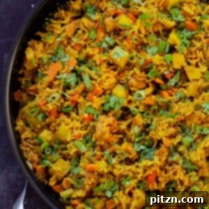 A vibrant pan of Vegan Jamaican Curry Rice, garnished with fresh cilantro and green onions, captured from an overhead view.