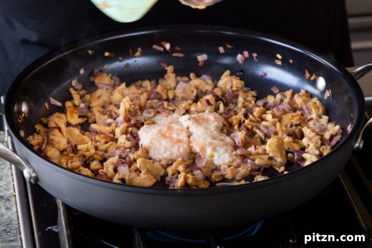 Simple One Pot Jamaican Curry Rice Gluten Free Nut Free 8 Adding hot sauce and ginger garlic paste to the sautéed soy curls and onions in the pan, stirring to combine the aromatics.