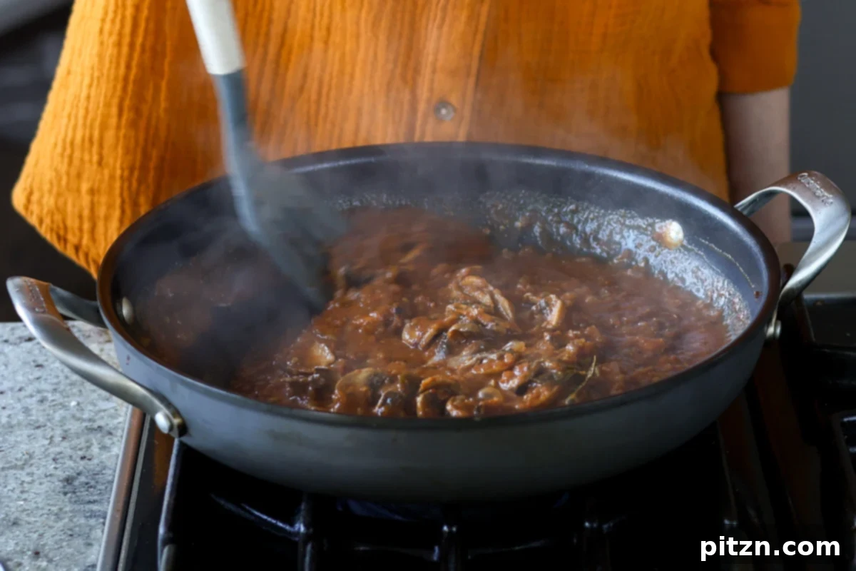 stirring the balchao mushrooms in the pan