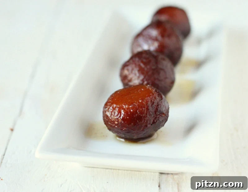 Vegan Gulab Jamun, soft and golden brown, soaked in clear sugar syrup.