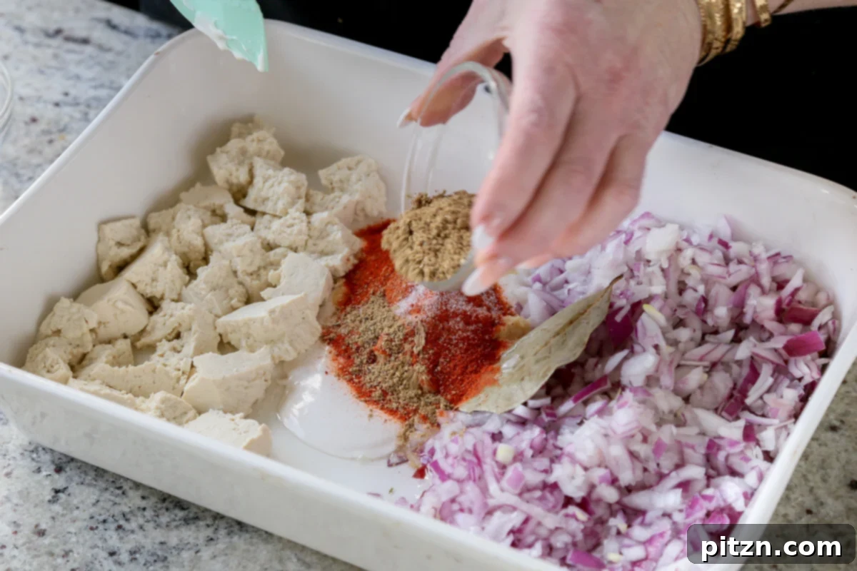 The previously prepared powdered spice mix is generously sprinkled into the center of the baking pan, joining the ginger garlic paste and yogurt.