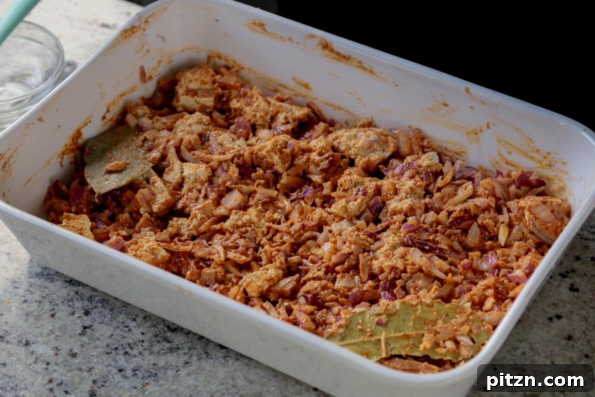 The baking pan contains seasoned tofu and onions, perfectly prepped and separated, ready to be placed into the oven for the first bake.