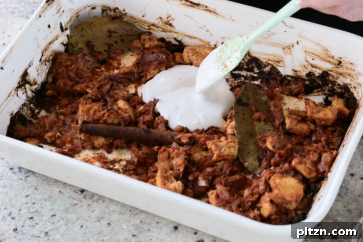 Non-dairy yogurt is added to the baked tofu and onions in the pan, preparing the base for the rice.