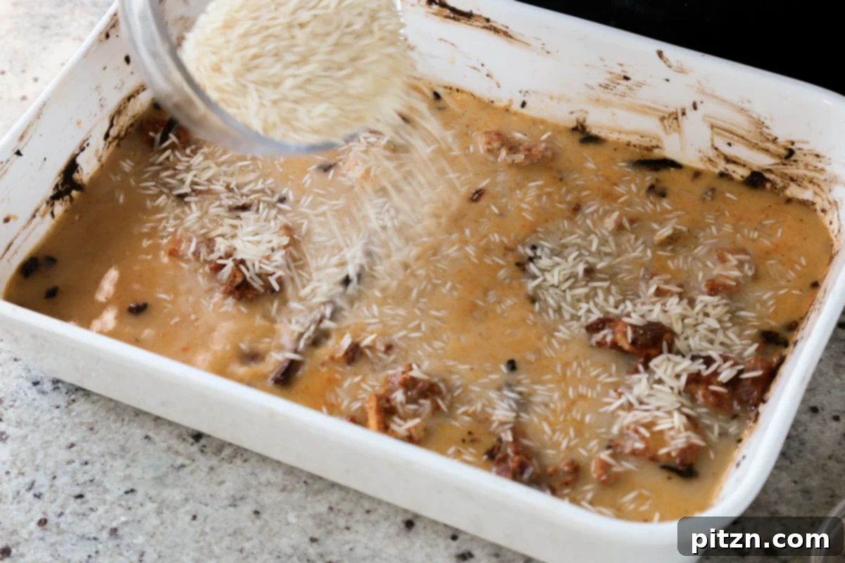 Washed basmati rice and hot broth are carefully added to the baking pan, combining with the spiced tofu and onions.