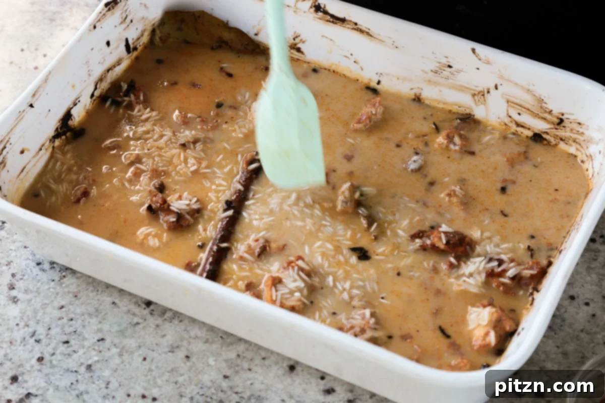 The rice, broth, and other biryani ingredients are gently mixed in the pan, creating an even layer before the final bake.
