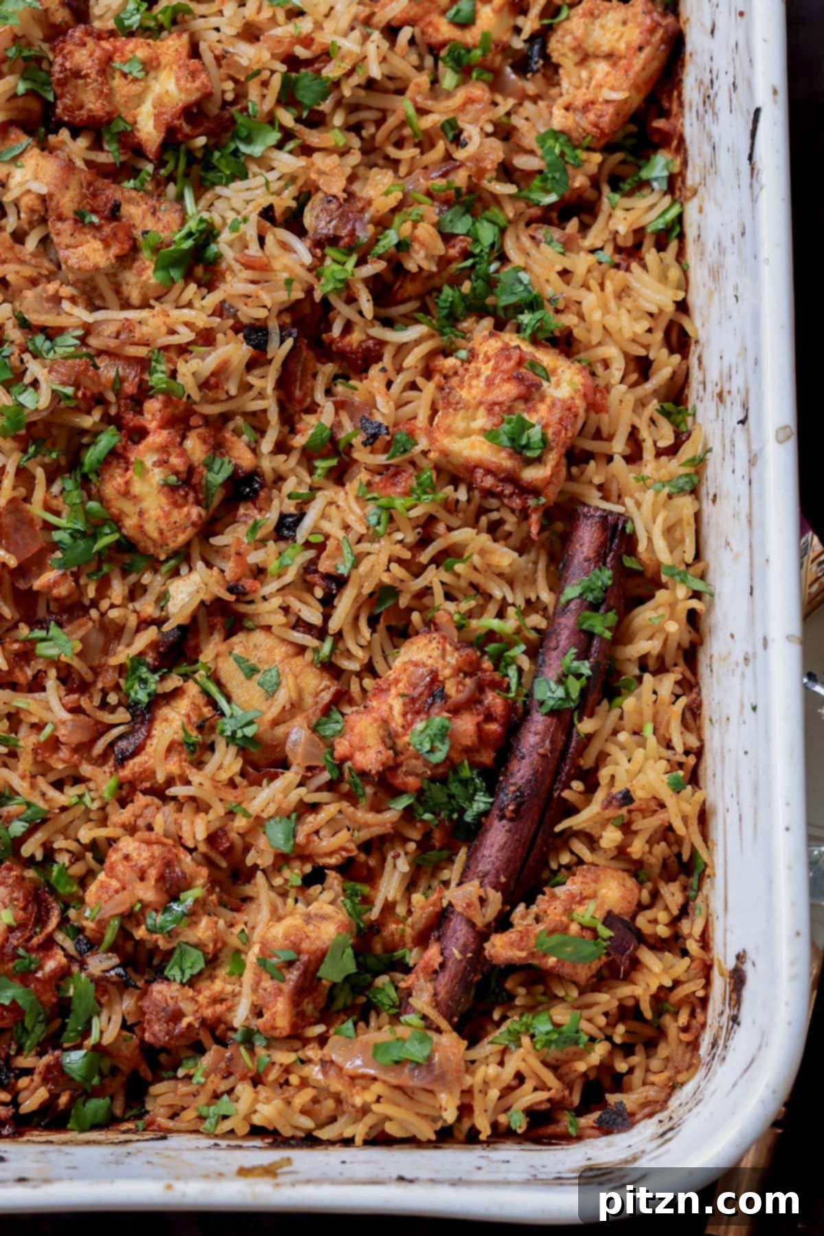 A close-up view of baked Lucknowi Biryani in the pan, highlighting the perfectly cooked rice, spiced tofu, and aromatic ingredients.