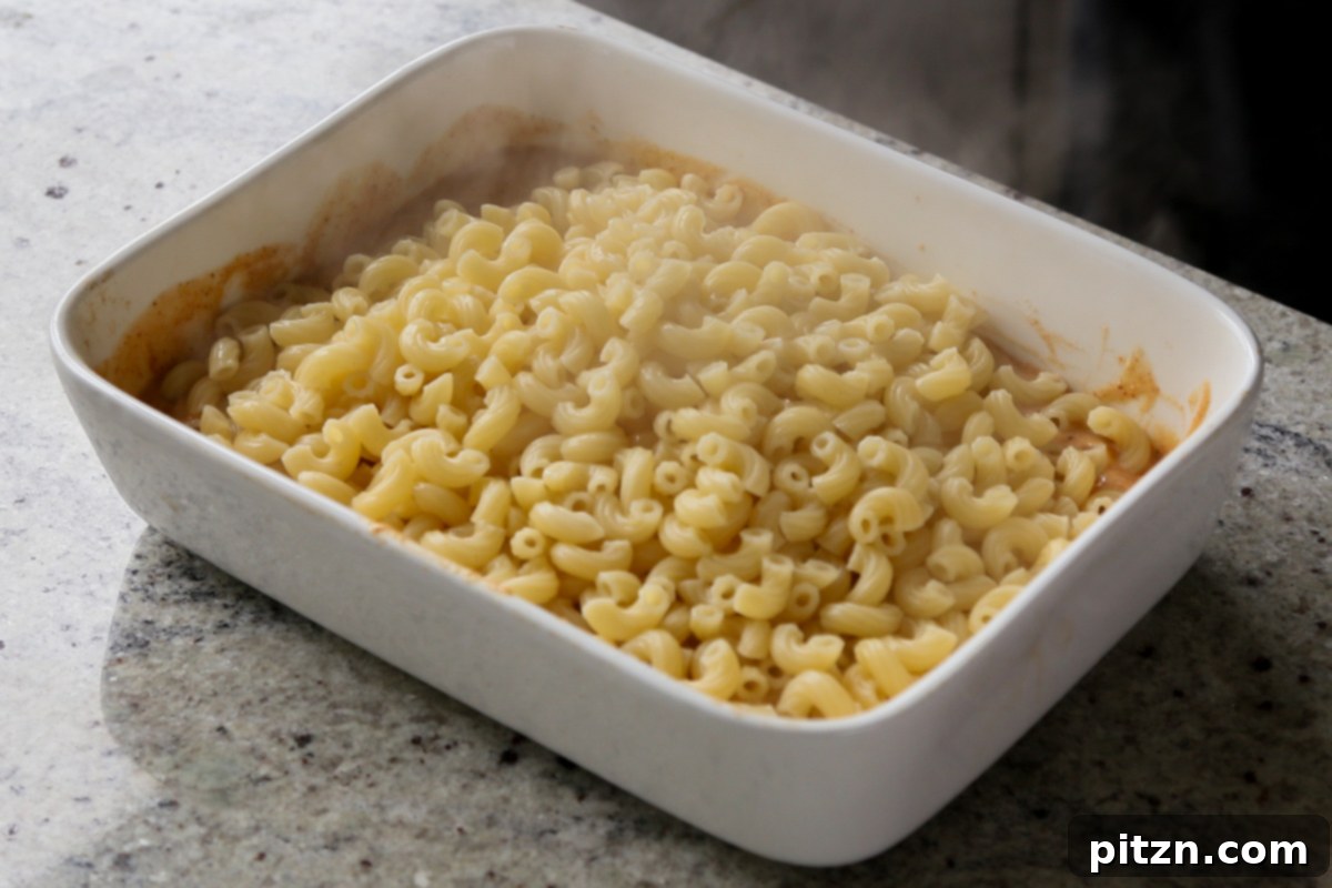 Creamy Smoky Vegan Mac and Cheese Bake 12 adding pasta to the pan of vegan smoky cheese sauce