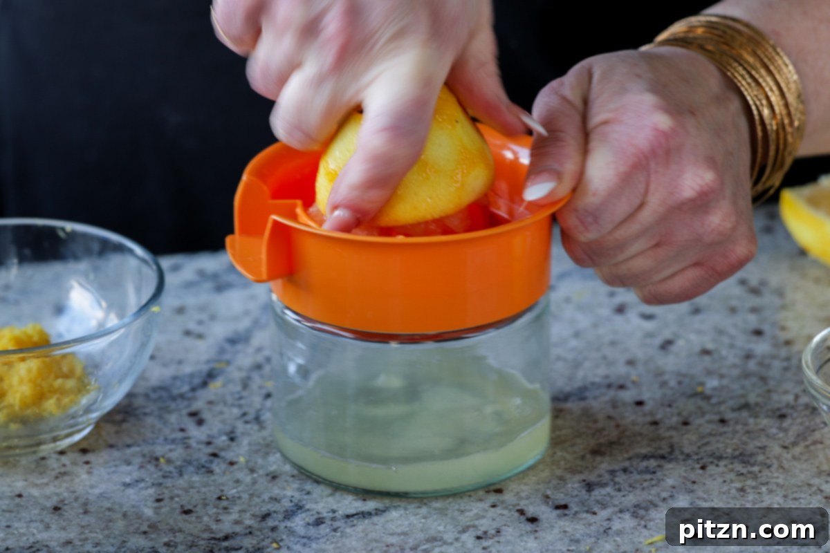 Zesty Vegan Lemon Cloud Cake 10 Hand juicing a freshly zested lemon into a bowl on a kitchen counter