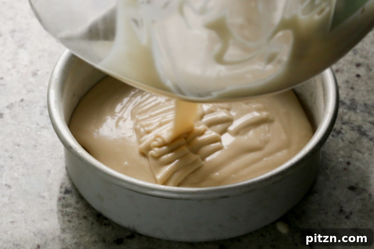 Zesty Vegan Lemon Cloud Cake 14 Half of the vegan lemon cake batter being poured into a prepared round baking pan