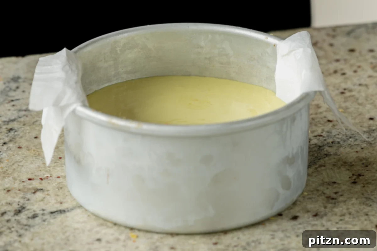 Zesty Vegan Lemon Cloud Cake 21 Generously applying lemon frosting to the first layer of vegan lemon cake in the pan