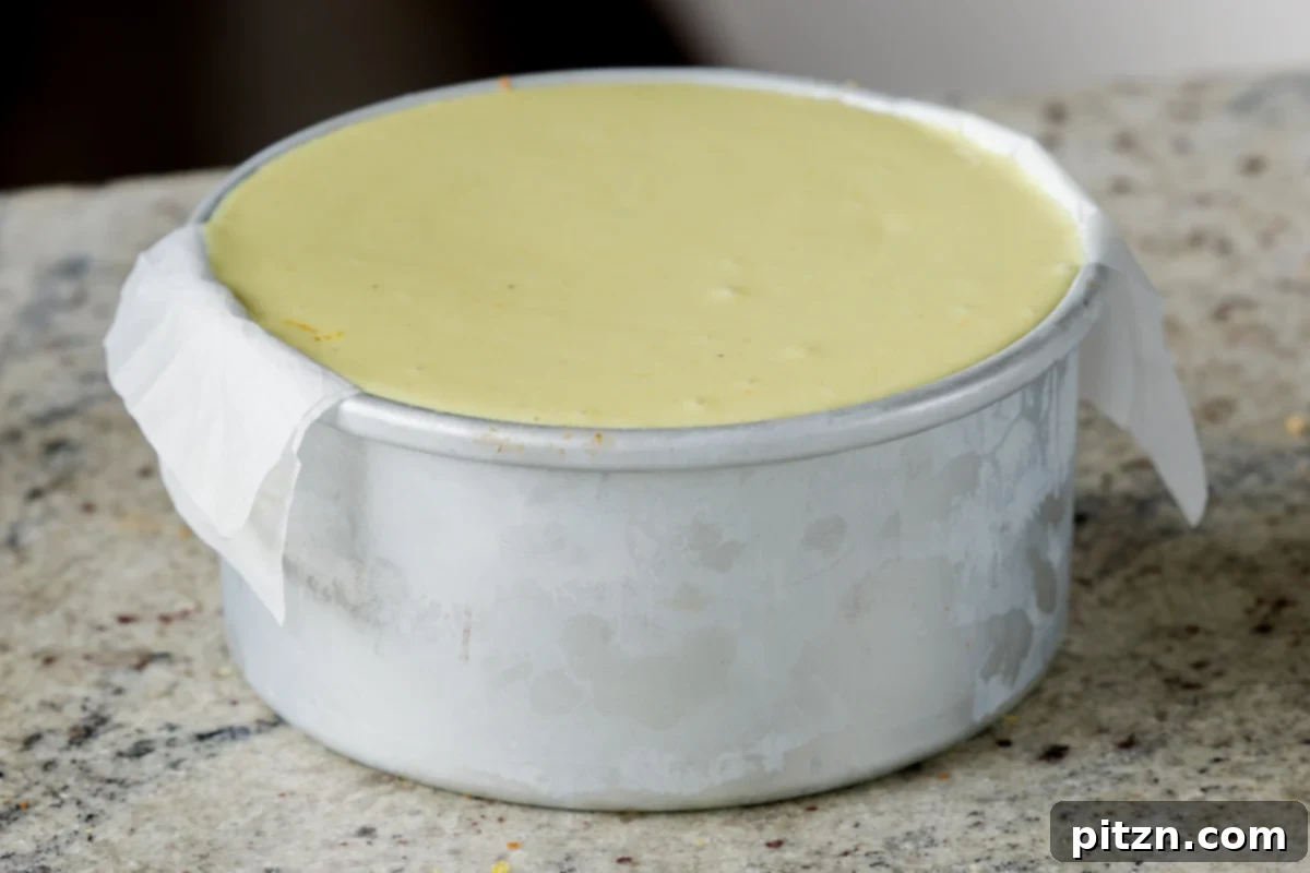 Zesty Vegan Lemon Cloud Cake 23 Applying the second layer of creamy lemon frosting to the top of the stacked vegan cake layers in the pan