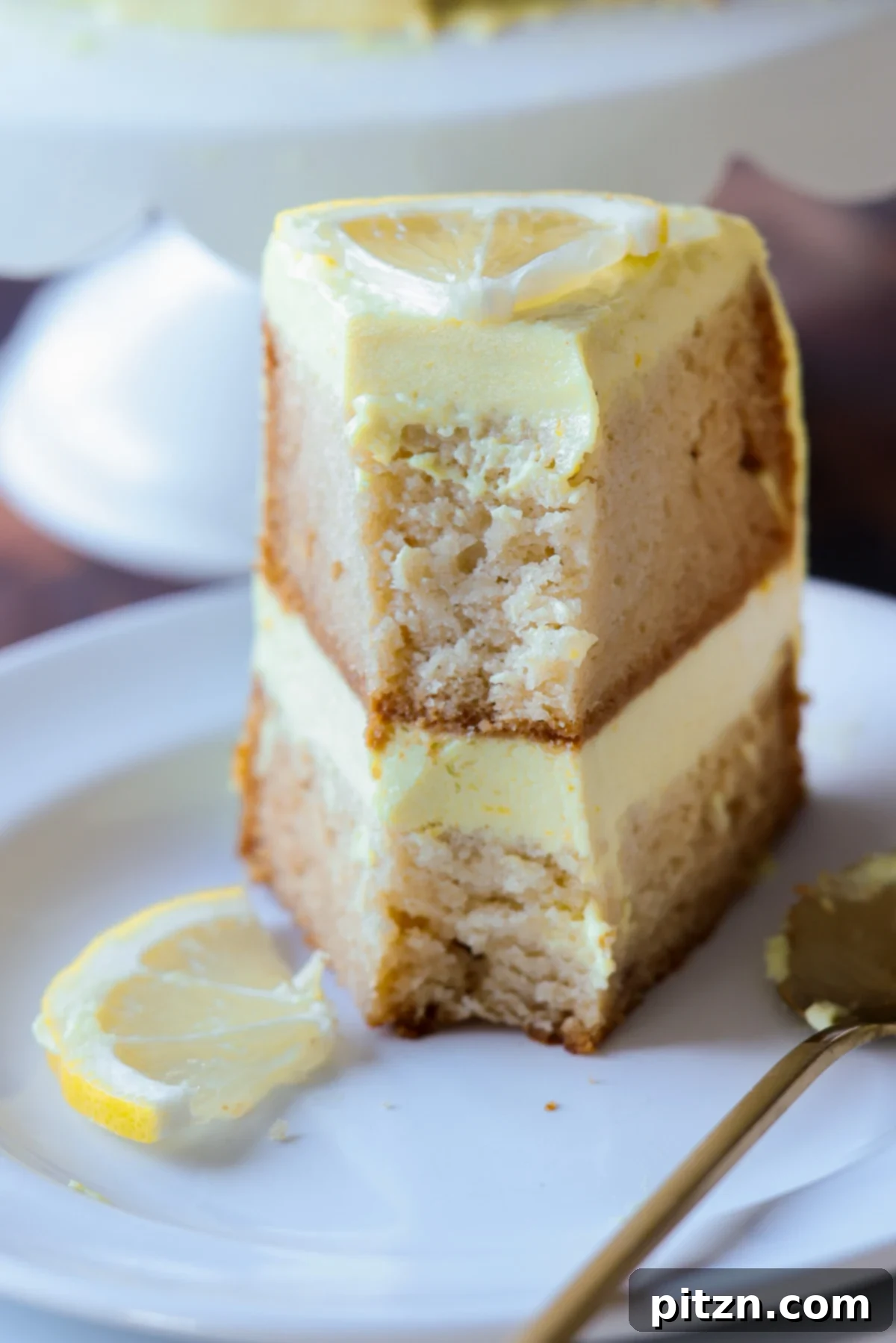 Zesty Vegan Lemon Cloud Cake 5 Vegan lemon cake displayed on a cake stand with slices ready for serving, showcasing its appealing texture