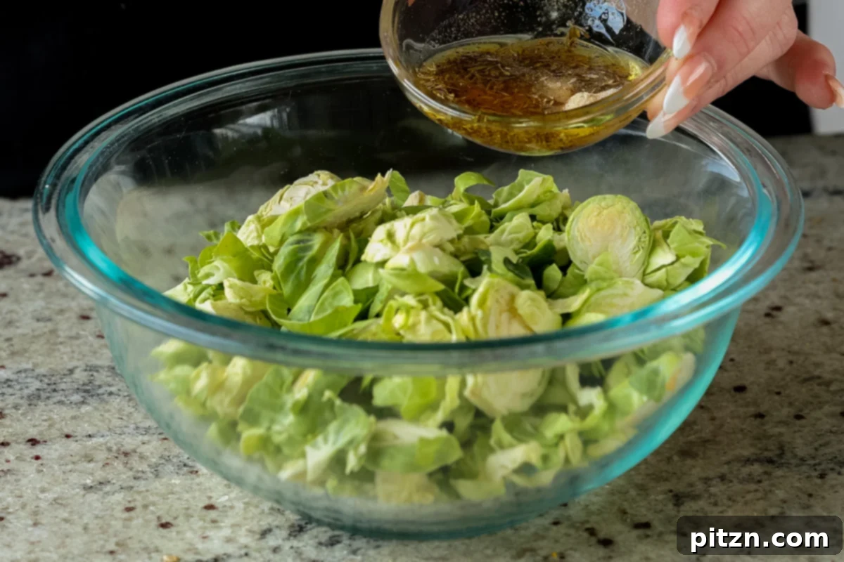 Roasted Shaved Brussels Salad with Walnut Crumble 8 mixing seasonings over the bowl of Brussels sprouts