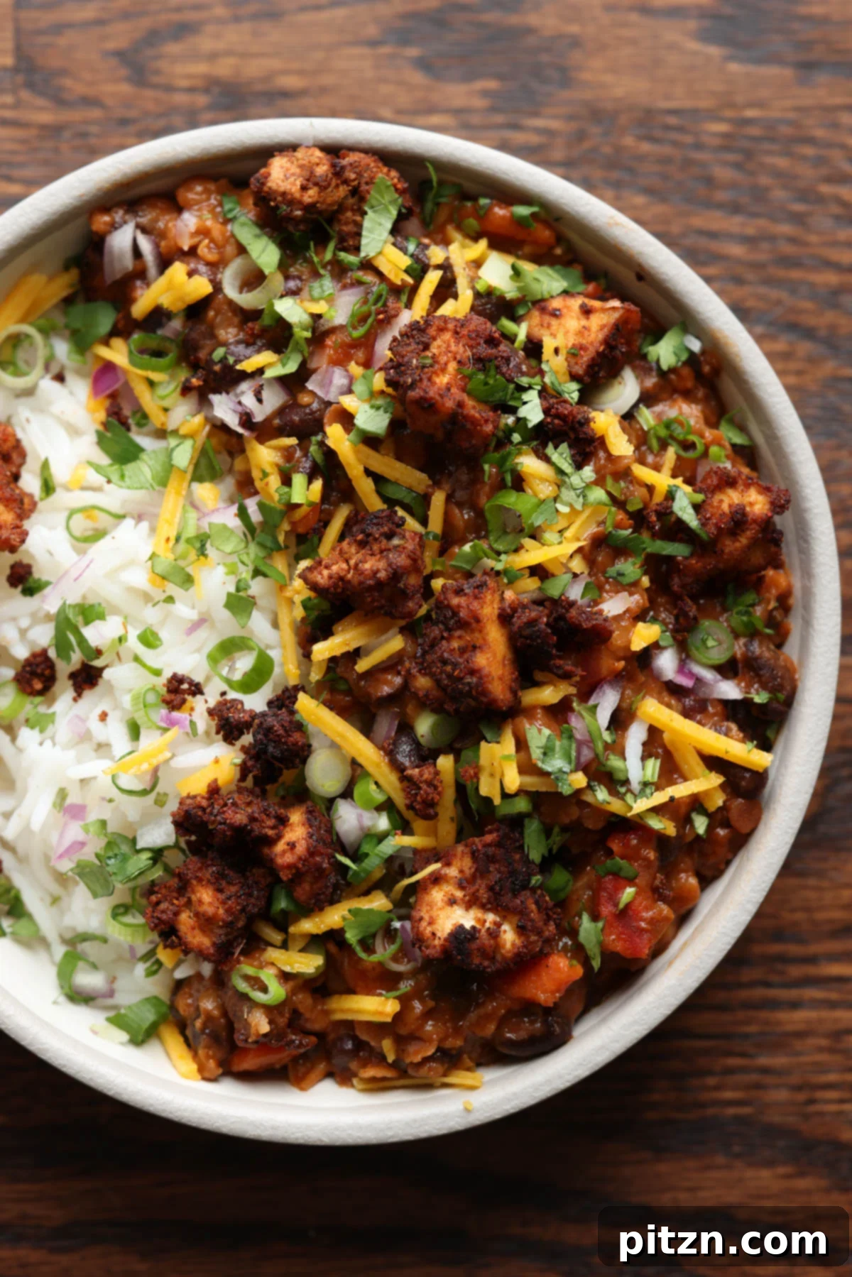 Vibrant Chorizo Tofu Burrito Bowl with rice, fresh pico de gallo, and a dollop of creamy vegan cheese on top, ready to be enjoyed.