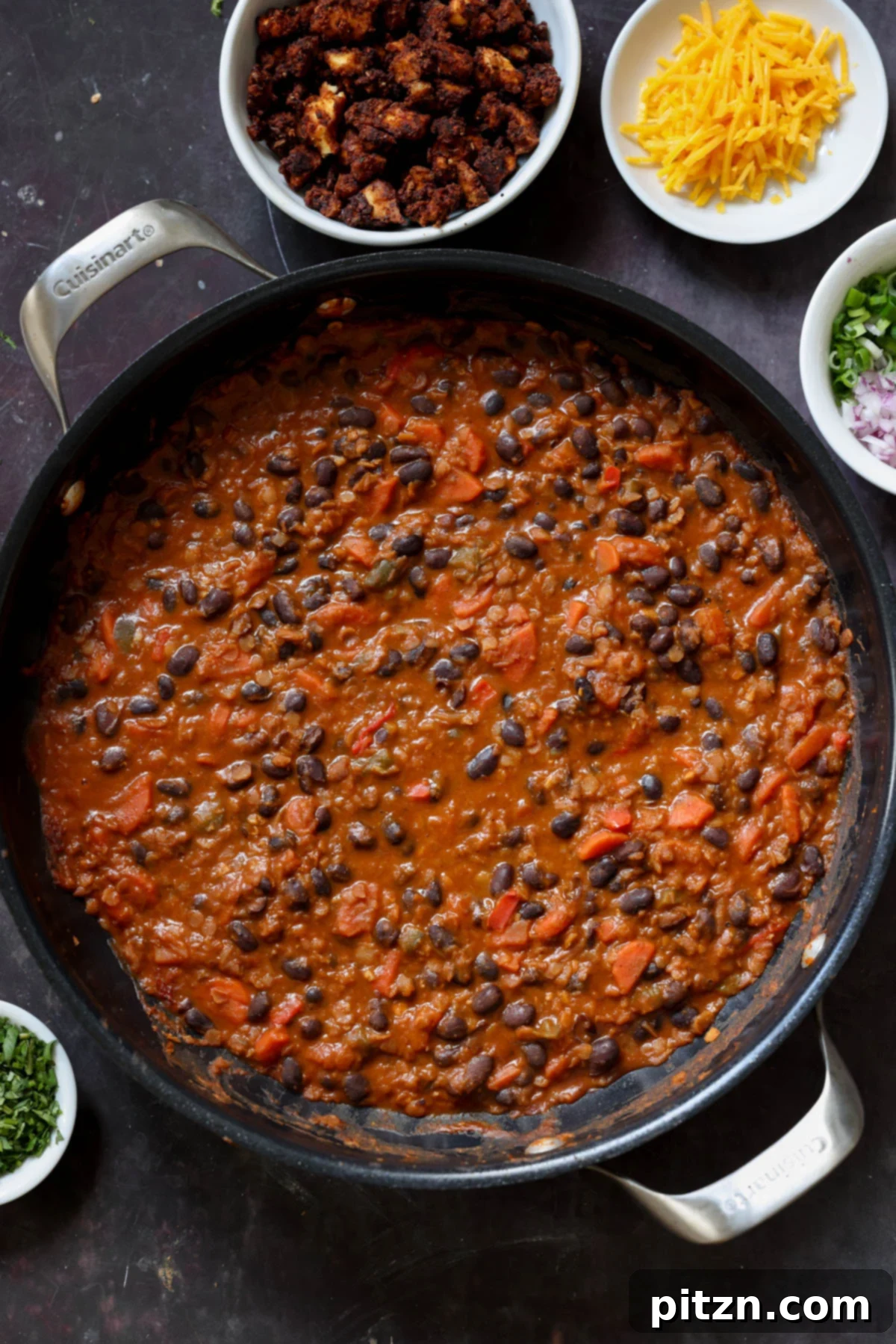 A pan filled with cooked black beans and red lentils, before adding any fresh toppings, showcasing the rich, stew-like texture.
