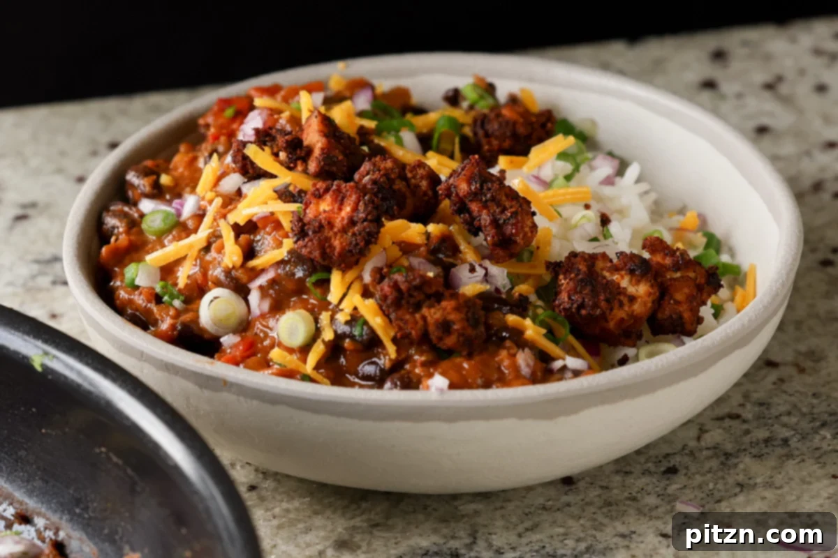 A beautifully presented chorizo tofu burrito bowl with rice, garnished with pico de gallo, vegan cheese, and fresh cilantro, ready to eat.